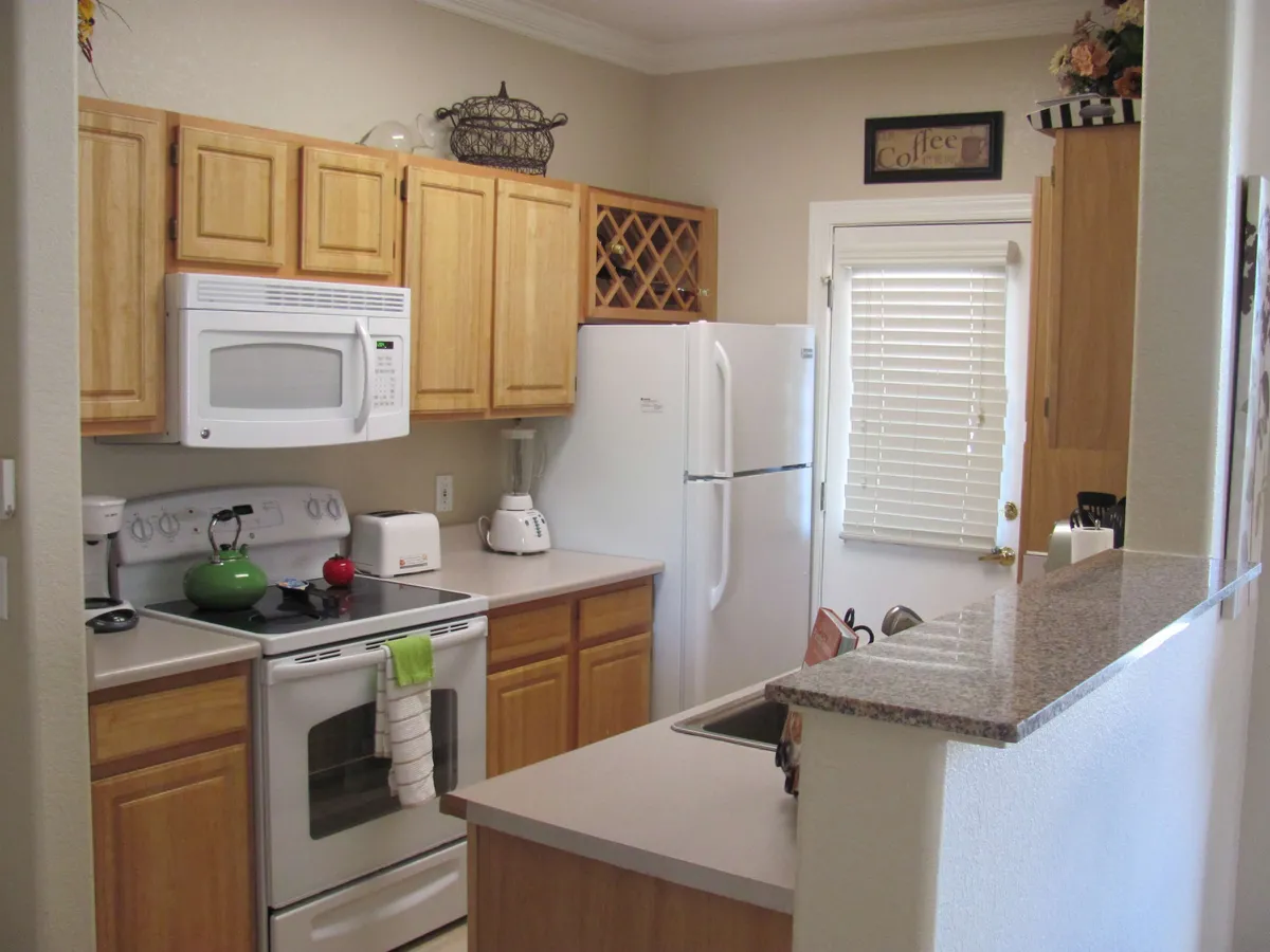 This image presents a modern kitchen with stainless steel appliances, wooden cabinetry, and granite countertops. Decorative items add a warm touch, while the overall layout suggests a recently renovated and fully equipped space for both everyday cooking and entertaining.