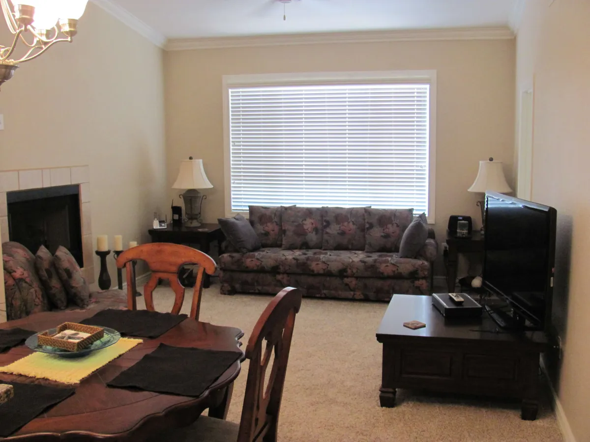 This image features a cozy living room with a sofa, dining table, television, fireplace, and lamps. The arrangement is perfect for both relaxing and gathering with loved ones, while the lighting and décor promote a feeling of security and comfort.