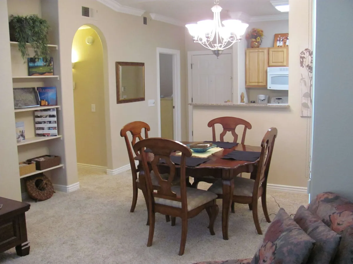 A cozy dining area with a central table, illuminated by a stylish chandelier and surrounded by a bookshelf. The scene evokes togetherness, making it ideal for family meals, sharing stories, or celebrating special occasions.